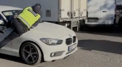 Un polițist a fost luat pe capota unei mașini, după ce a încercat să documenteze șoferul pentru parcare neregulamentară - Photo
