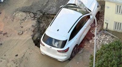 Un Ford a rămas blocat într-o groapă, după ce s-a surpat asfaltul în locul unde era parcat - Photo
